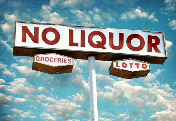 aged and worn No liquor store sign with clouds