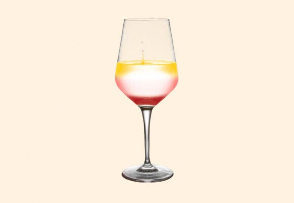 A wine glass full of 3 types of wine